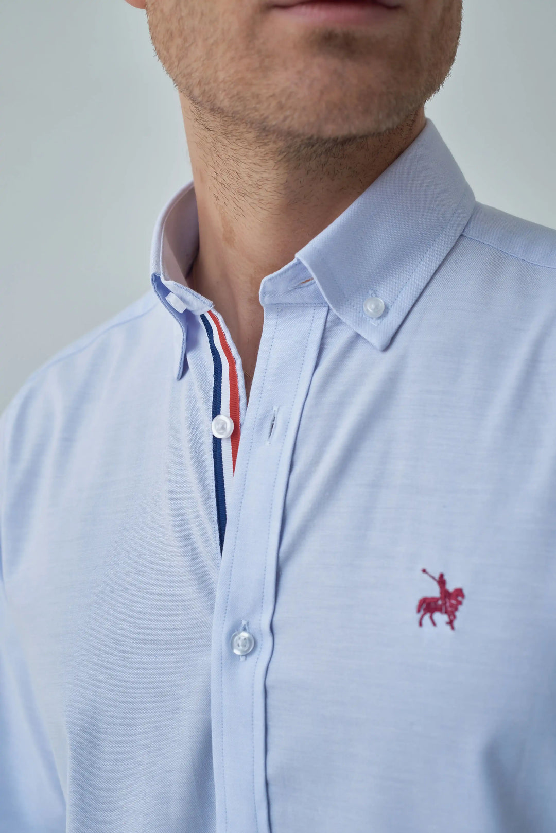 Camisa azul claro para hombre. Camisa con detalles de colores bandera de Francia en el cuello. Logo bordado rojo.