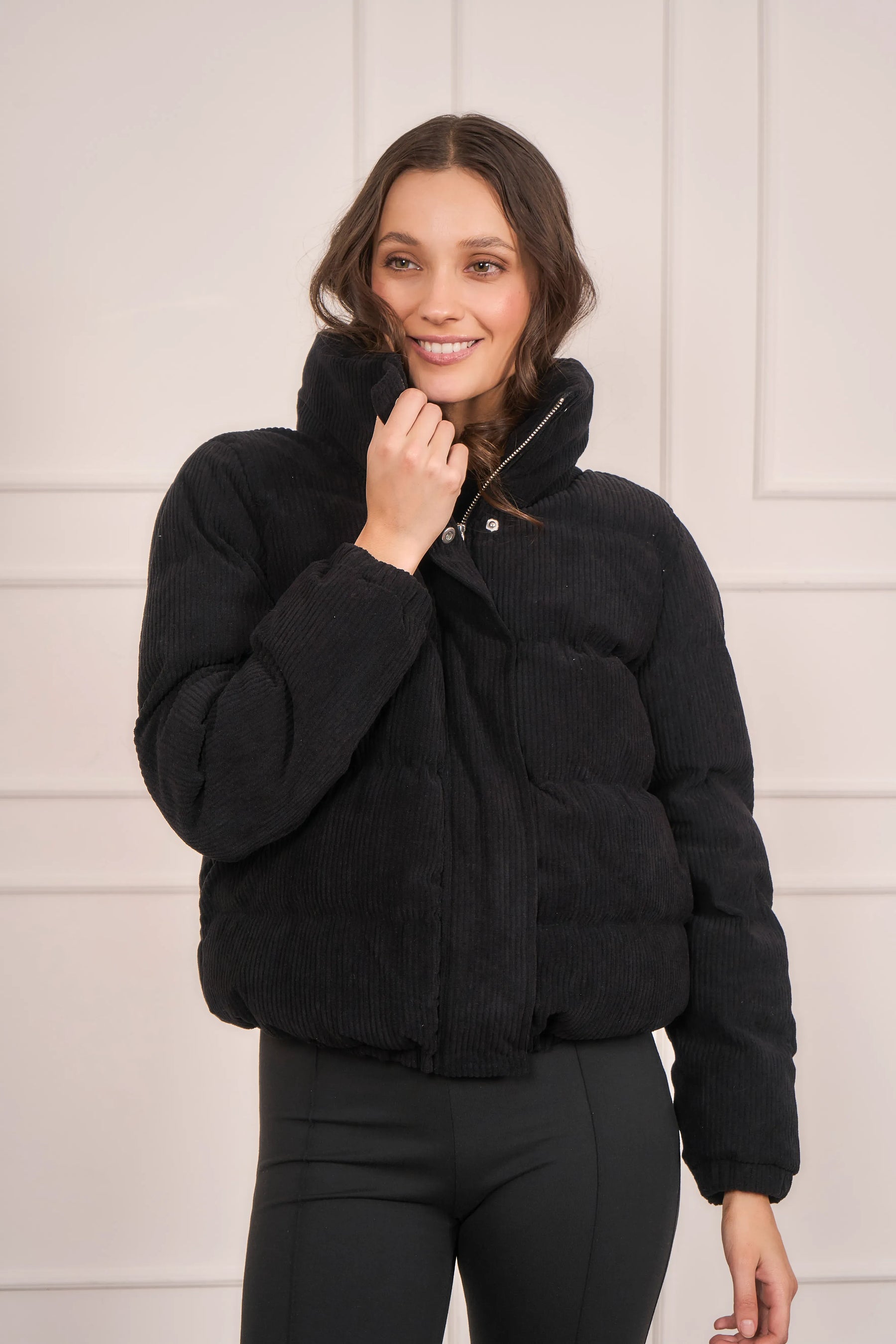 Mujer con chaqueta tipo puffer de color negro y textura semi acanalada 
