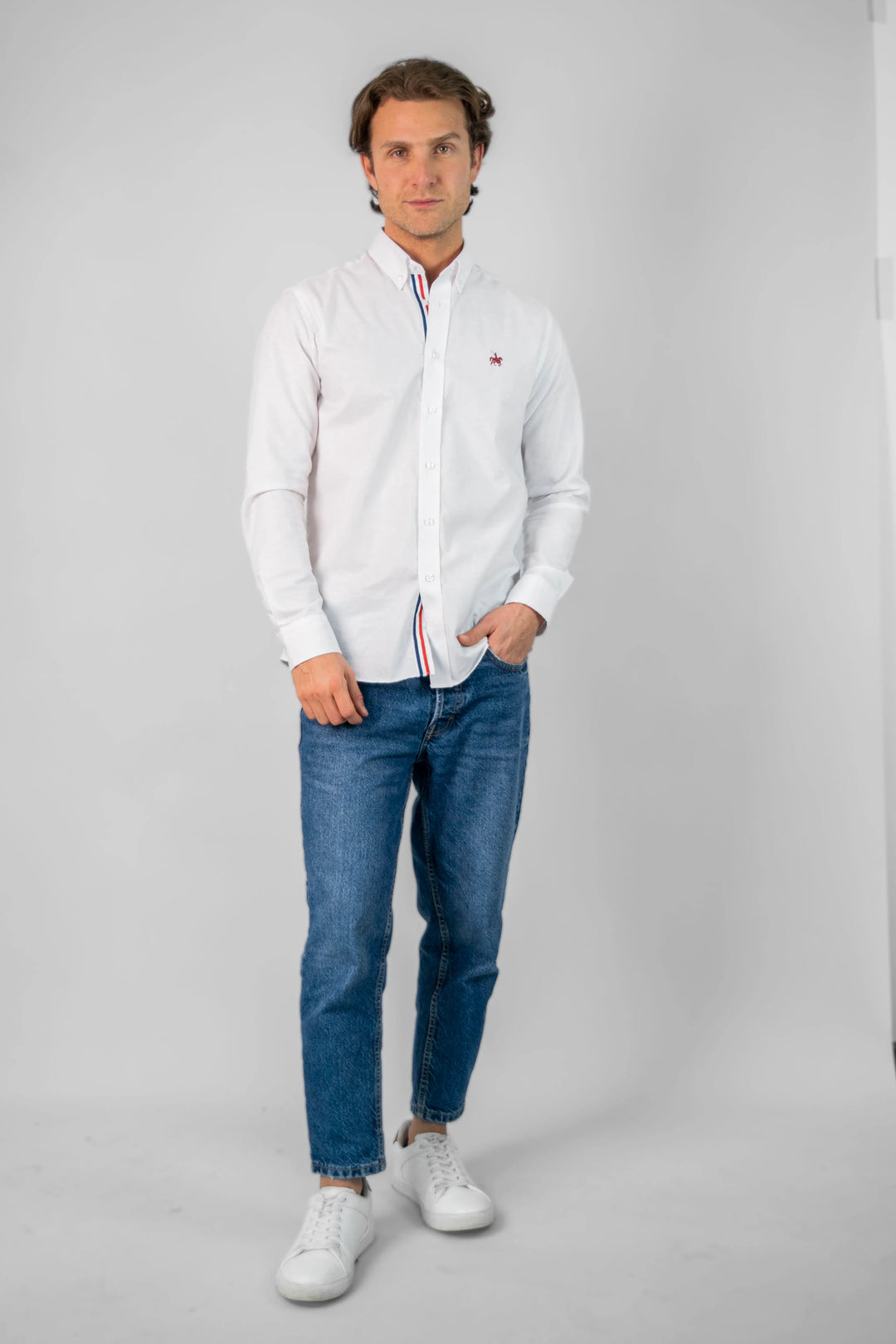 Modelo masculino de pie vistiendo la camisa manga larga France, combinandola con unos jeans y unos zapatos blancos casuales. Camisa ideal para looks formales e informales.