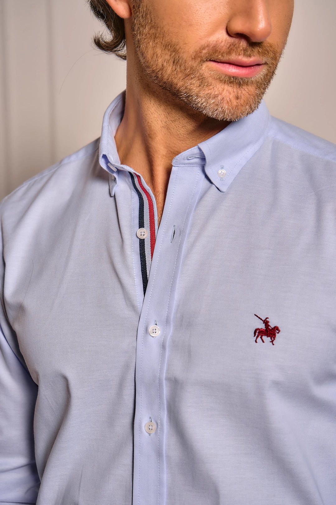 Camisa azul claro para hombre. Camisa con detalles de colores bandera de Francia en el cuello. Logo bordado rojo.