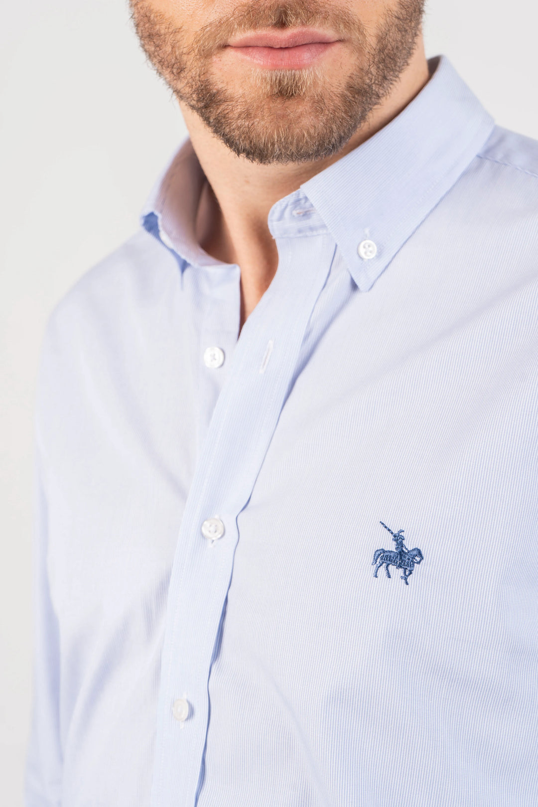 Camisa hombre azul clara manga larga. Imagen detalle del cuello y logo bordado. Camisa ideal para ocasiones formales.