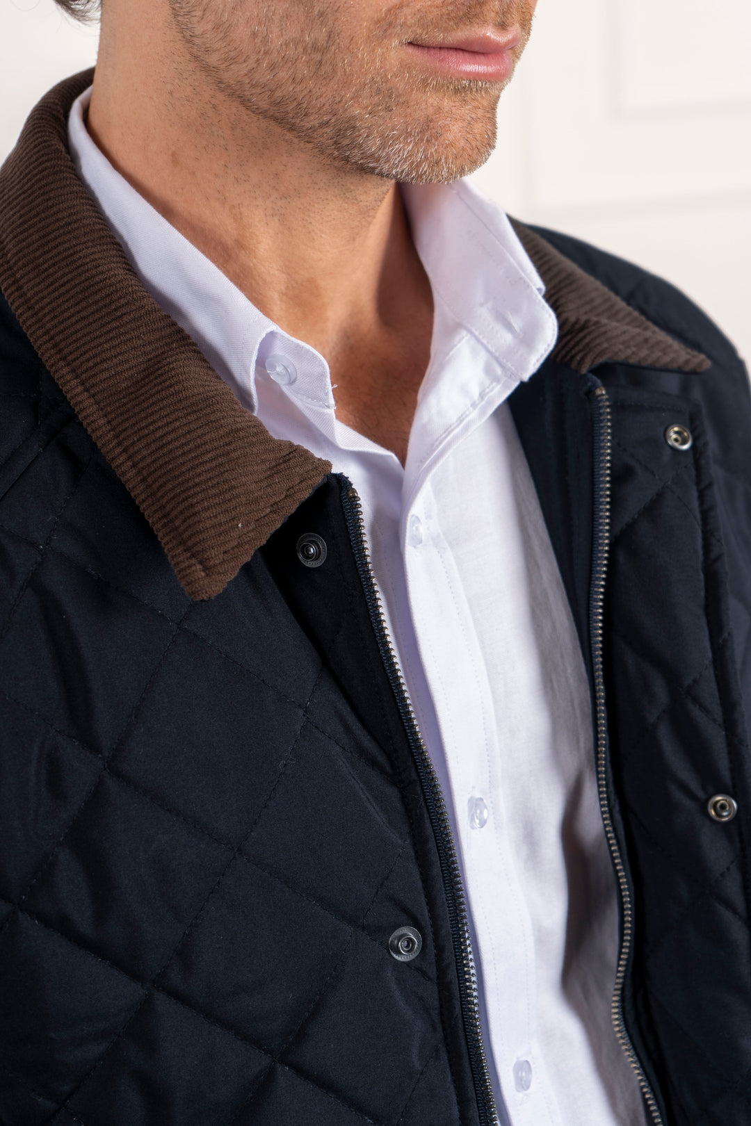 Detalle del cuello de la chaqueta, combinada junto con una camisa blanca. Cierre de cremallera y botones.