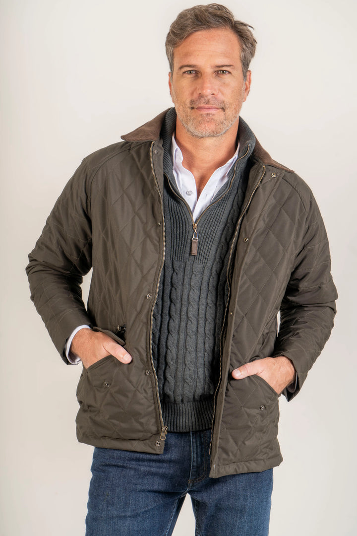 Modelo masculino sonriente vistiendo la Chaqueta. Cominada en un look atemporal, junto con un Suéter Halfzip trenzado y una camisa blanca manga larga para hombre